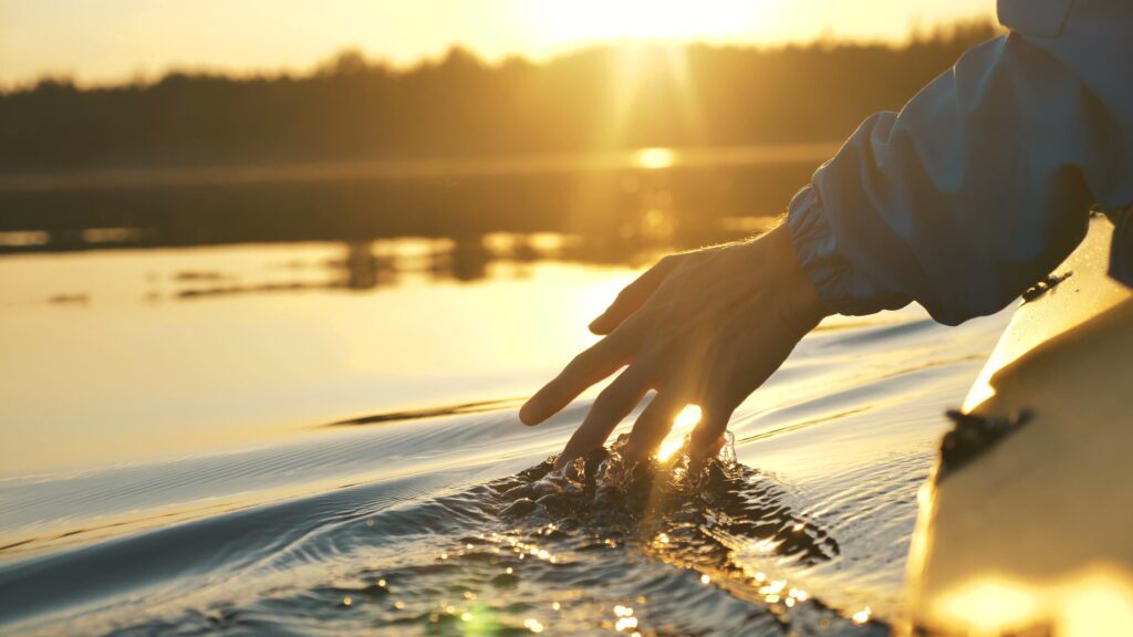 hope restored family counseling website man puts fingers down lake kayaking against backdrop of golden sunset, unity harmony nature